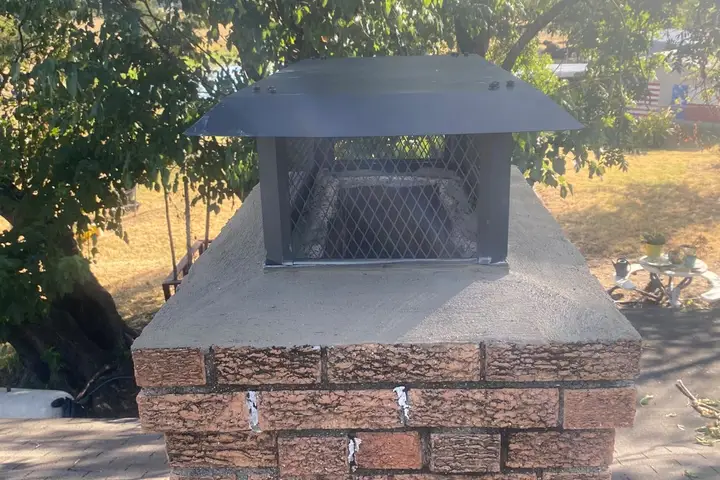 New chimney cap installed on a brick chimney