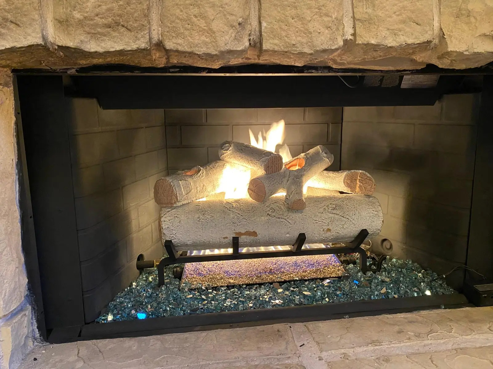 Vented gas log set burning in a brick fireplace