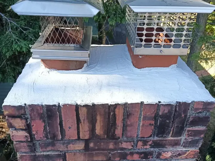 Two stainless steel chimney caps on a repaired brick chimney