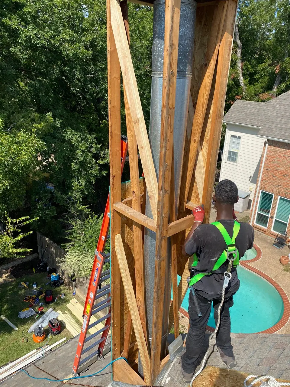 Crownline technician in a safety harness working on a chimney chase